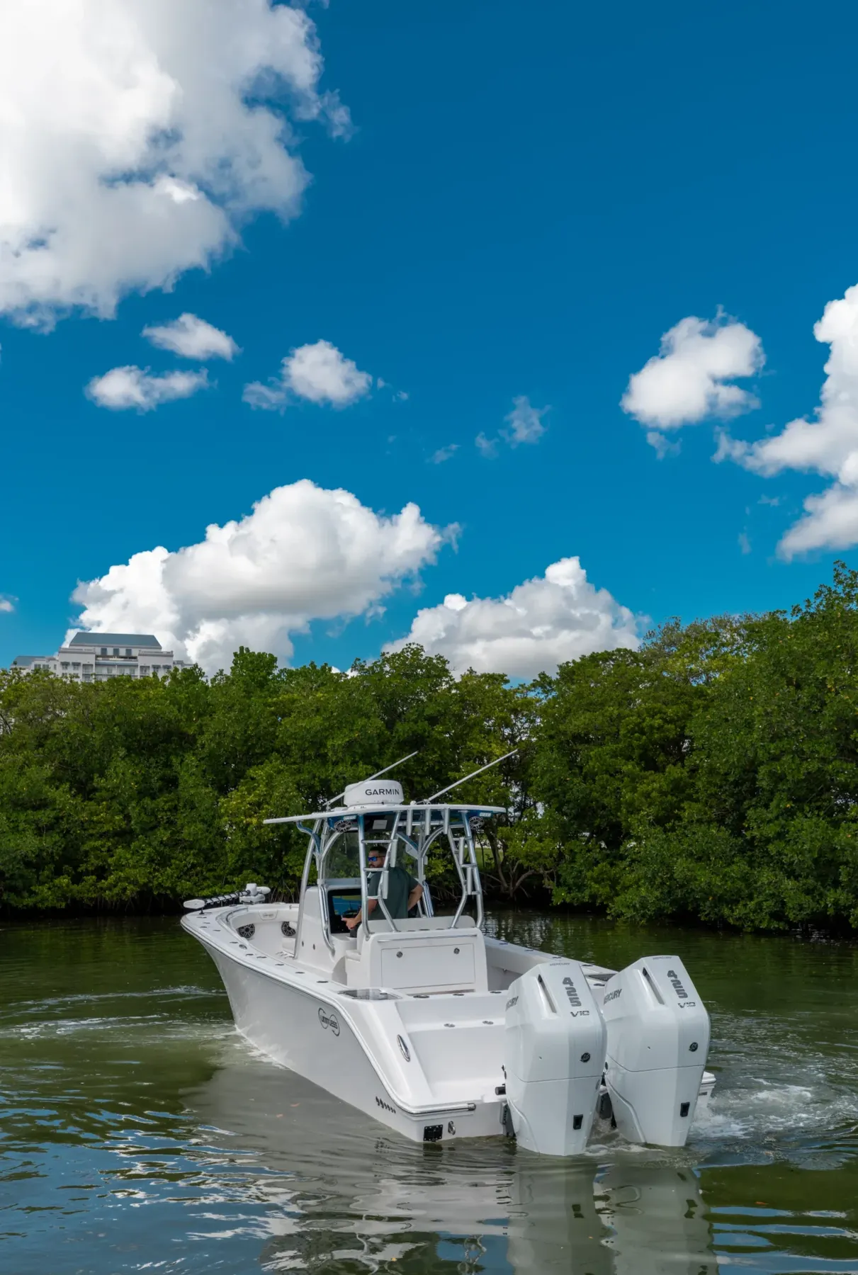Limitless 320 with twin Mercury outboards running past the mangroves